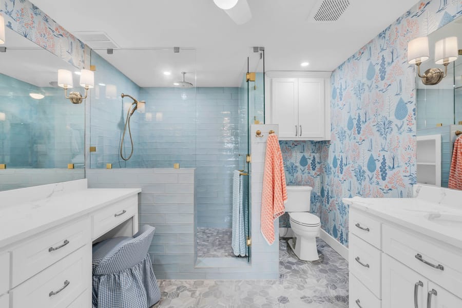 Primary bathroom remodel with blue floral wallpaper, marble double vanity and brass fixtures